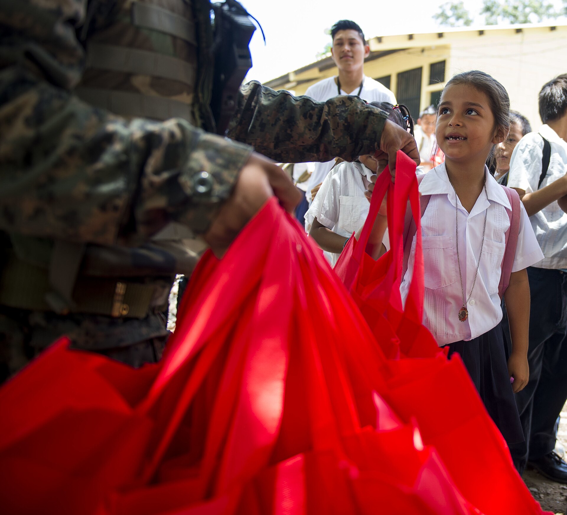 Un écolier de l'école Gabriela Mistral à Ocotes Alto, Honduras, a reçu une aide humanitaire d'un soldat du 15e bataillon de l'armée hondurienne le 20 juillet 2015. Le personnel de l'exercice d'entraînement New Horizons Honduras 2015 a visité Gabriela Mistral pour livrer des sacs fourre-tout, des sacs à dos, des livres et de la nourriture dans le cadre de la mission d'aide humanitaire organisée par des soldats des affaires civiles du 81e bataillon des affaires civiles de Fort Hood, Texas. New Horizons a été lancé dans les années 1980 et est un exercice annuel conjoint d'assistance humanitaire