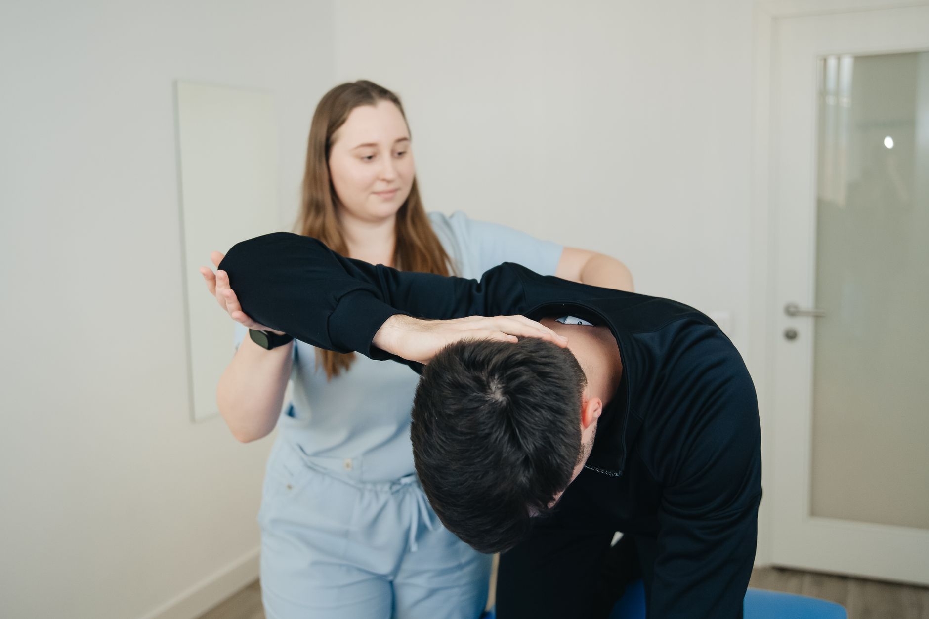Une physiothérapeute guide un patient lors d'une séance de rééducation en salle